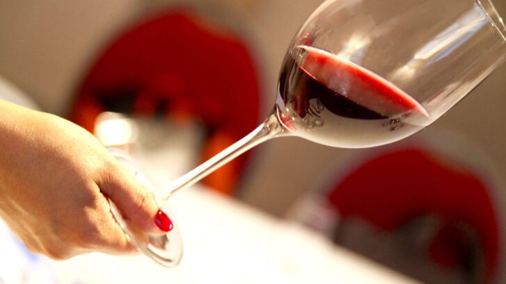 Main tenant verre de vin rouge pour identifier les couleurs et nuances d'un vin